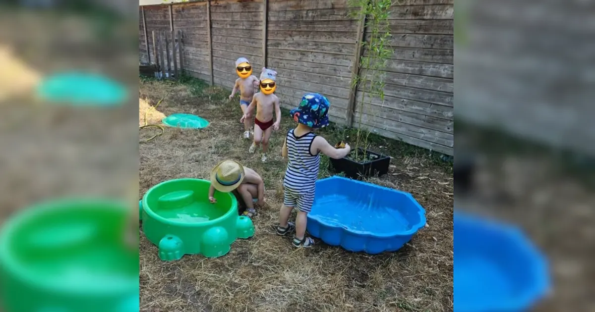 Tout-petit jouant avec une bassine d'eau posée au sol dans le jardin d'une micro-crèche à Sélestat